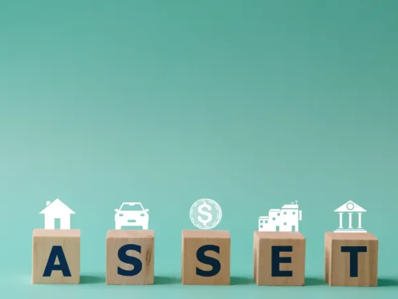 Wooden blocks spelling "ASSET" with icons of a house, car, dollar sign, factory, and bank above.